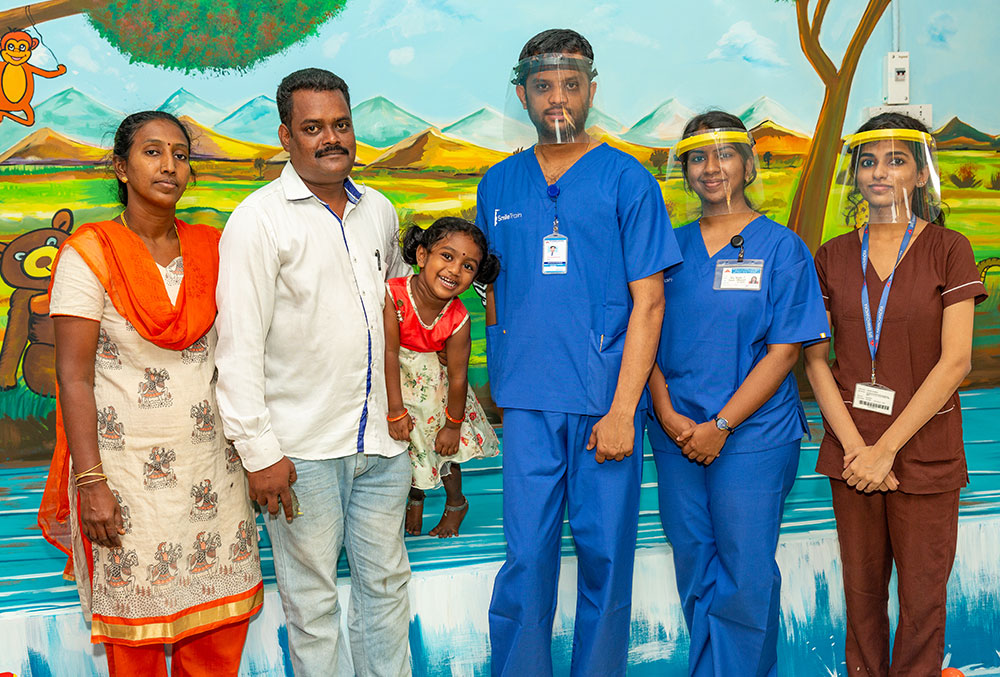Jaya smiling with her parents and hospital staff