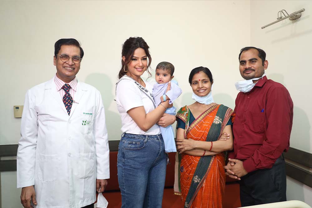 Harnaaz Sandhu smiling and holding a cleft patient with their parents and doctor