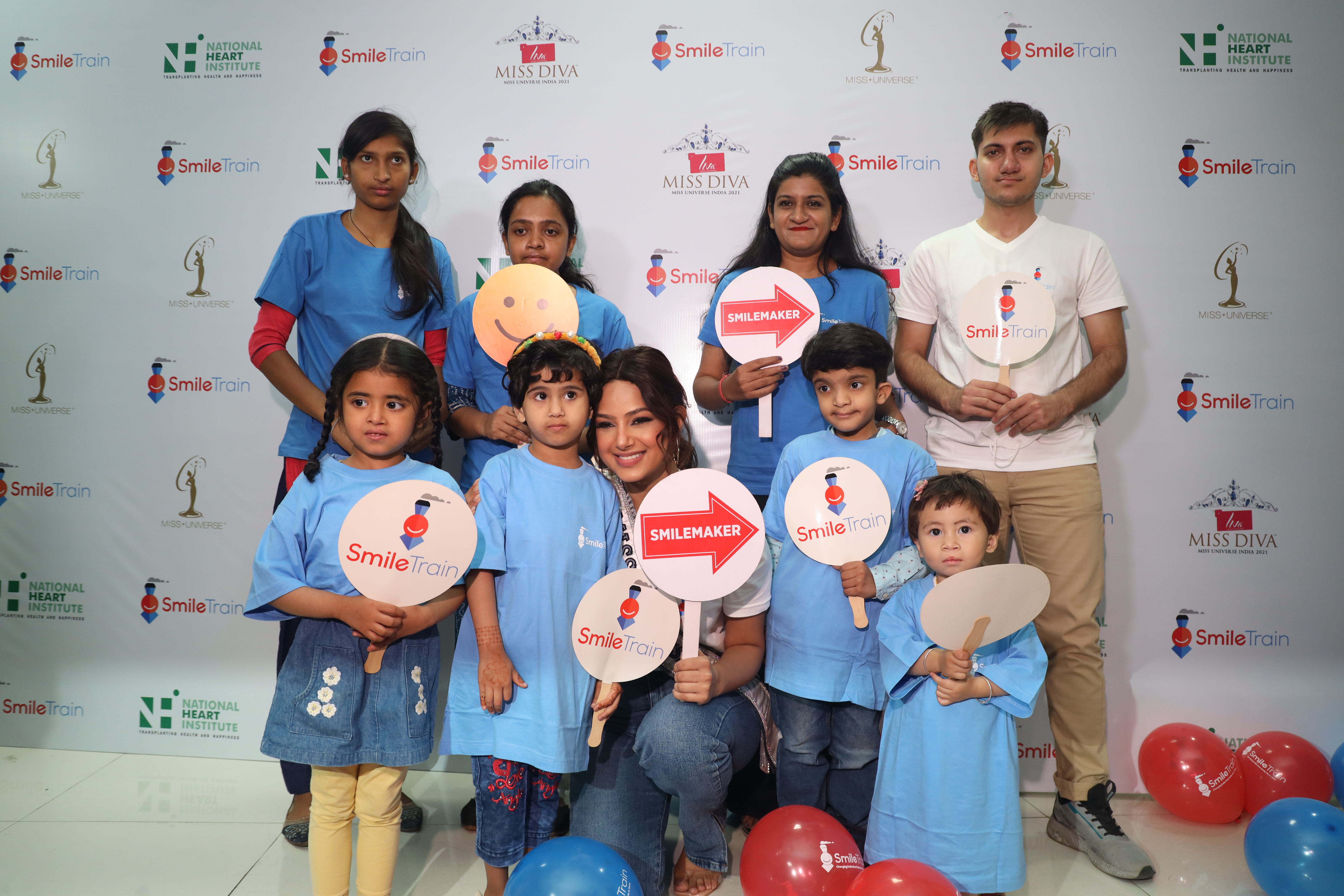Harnaaz Sandhu smiling with patients and holding Smile Train signs