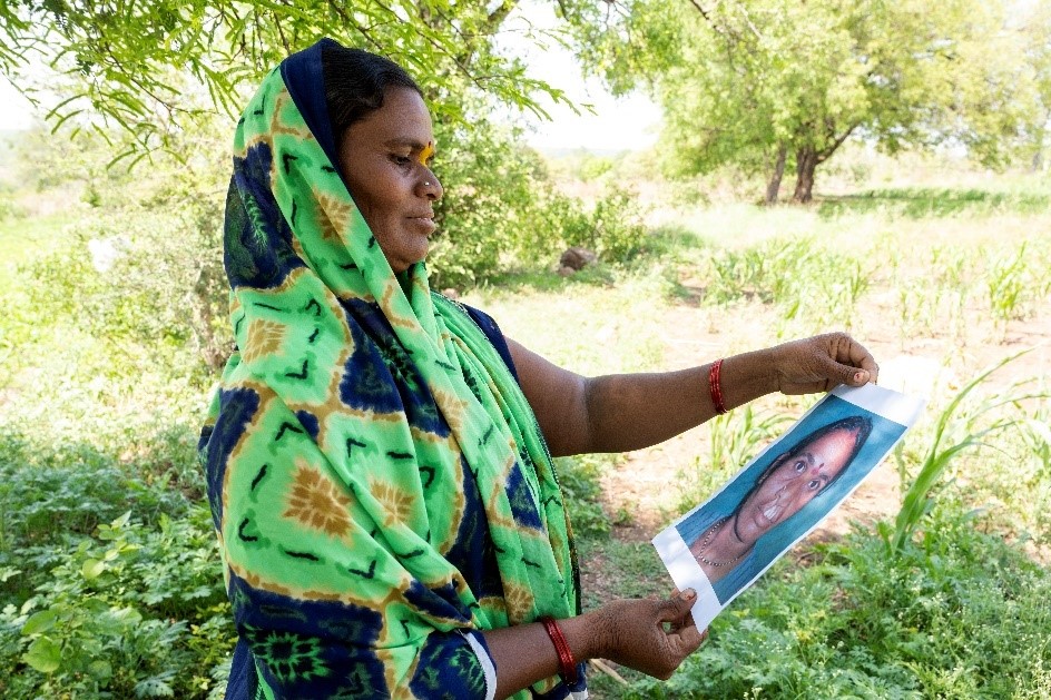 Surekha smiling and holding a picture of herself before cleft surgery