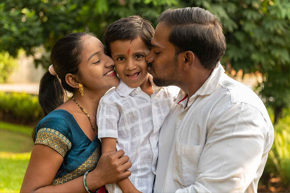 Manthan getting kissed by his parents, one on each cheek