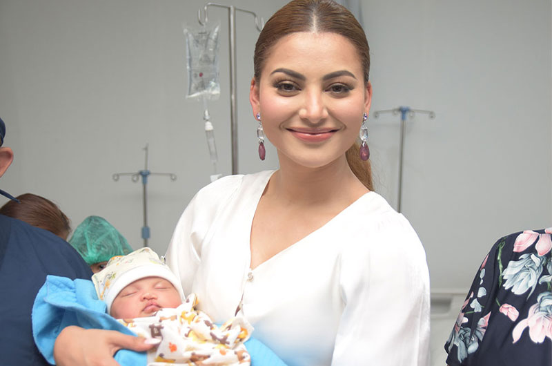 Urvashi Rautela smiling and holding a cleft-affected baby