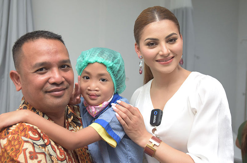 Urvashi Rautela smiling with a Smile Train patient and their father
