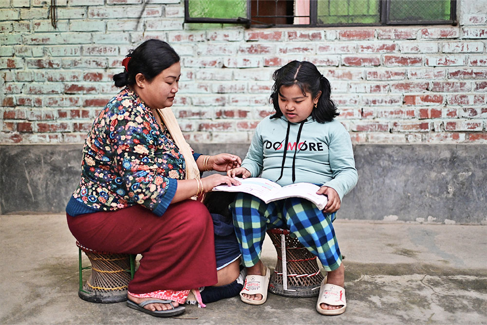 Bena sitting and reading with her mother Romila after cleft surgery