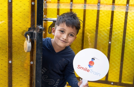Abhay smiling and holding a Smile Train sign after cleft surgery