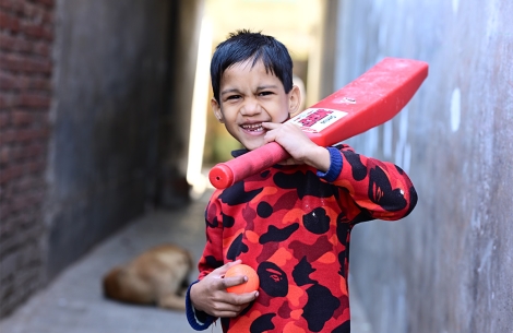 Hussain smiling and holding a cricket bat after cleft surgery