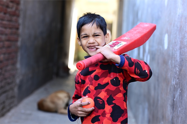 Hussain smiling and holding a cricket bat after cleft surgery