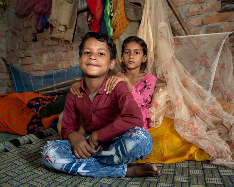 Shubham sitting with his sister's hands on his shoulders after cleft surgery