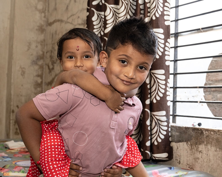 Abhay smiling and giving his sister a piggyback after cleft surgery