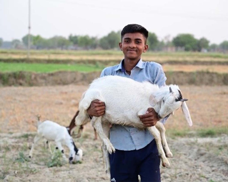 Monu smiling and holding a goat after cleft surgery